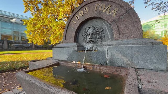Video of Saint Petersburg on sunny autumn day. Cityscape of Voronikhin Park with an ancient drinking fountain featuring mask of Neptune created in 1809. Architectural landmark. Travel and Sightseeing