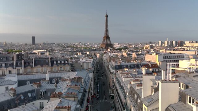 Aerial drone view of the sleepy streets of Paris, France, overlooking the famous Eiffel Tower and Champ de Mars at sunrise or sunset. Low motion over the rooftops. Cinematic 4k. Europe from above.