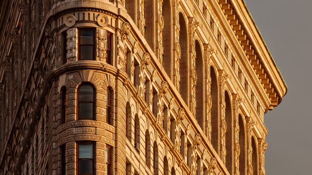New York City, NY, USA &ndash; June 19, 2020: Detailed view of the Flatiron Building facade illuminated at sunset. Beaux-Arts architecture with intricate terra-cotta ornamentation