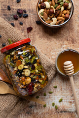 Assorted nuts with honey in a glass jar. Top view, vertical orientation, rustic style.