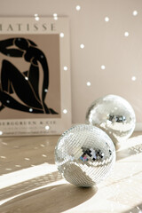 Sunlight reflects from disco balls, scattering dots across a modern wall.
Art print adds artful minimalism to the bright interior.
Sparkling decor creates a dreamy aesthetic atmosphere.