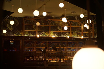 Elegant interior with lights and bar reflection: Captured the charm of an upscale bar interior with a warm ambiance, highlighting the elegant lighting and reflective surfaces.