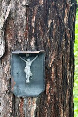 old incomplete Weathered crucifix on a tree trunk on a metal tombstone in nature