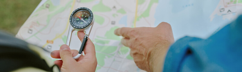 Obraz premium Hands of unrecognizable person pointing at paper map outdoors, focusing on navigation and route planning during adventure activity