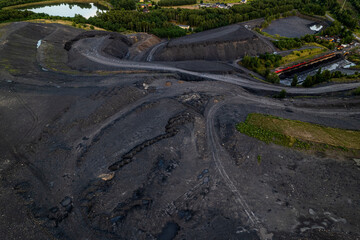 Fototapeta premium Red freight train transporting coal wagons railway track aerial view Rybnik Poland mining dump industrial vegetation horizontal landscape cargo