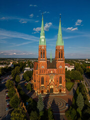 Fototapeta premium Close-up neo-Gothic red brick facade Basilica Saint Anthony Rybnik, Poland, vertical crop, natural lighting, tower details, ornate windows, commercial, architectural texture