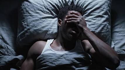 At Night, Tired Man Lies in White Bed, Moving Uneasily in Sleep Struggles With Nightmares. Concept of Stress, Anxiety, Restless Dreams, and Negative Effects of Overwork on Rest. Rotating Top View. 