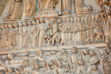 Close-up of religious sculptures on the facade of Notre Dame in Paris with stone-carved figures and Gothic architecture