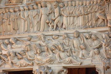 Close-up of religious sculptures on the facade of Notre Dame in Paris with stone-carved figures and Gothic architecture