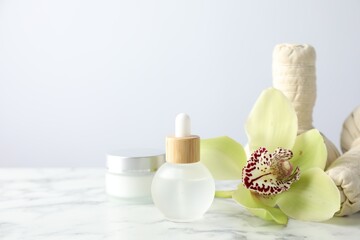 Beautiful spa composition with essential oil and herbal bags on white marble table against light background, closeup. Space for text