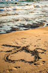 Heart shape drawn on sandy beach near gentle sea waves under golden sunlight symbolizing love, romance, summer vacation, wedding proposal, or coastal honeymoon atmosphere.
