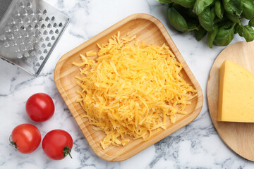 Grated cheese, grater and products on white marble table, flat lay