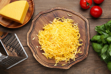 Grated cheese, grater and products on wooden table, flat lay