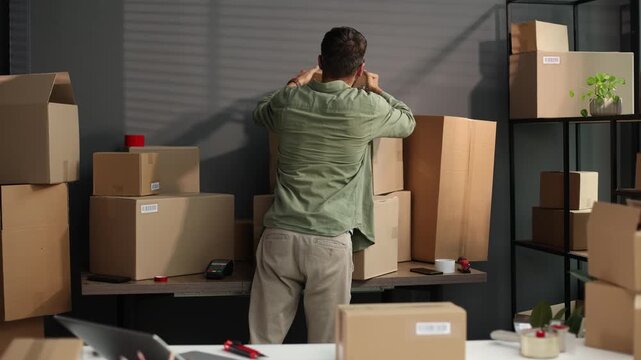 A man is standing in front of a pile of boxes, sorting through them