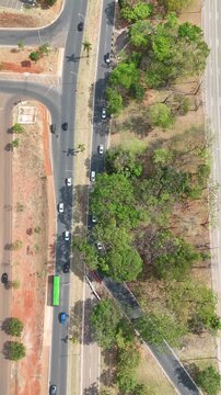 Imagem a&eacute;rea vertical mostrando o tr&aacute;fego intenso de ve&iacute;culos em uma avenida movimentada de Bras&iacute;lia, com faixas bem demarcadas, sinaliza&ccedil;&atilde;o urbana e fluxo constante