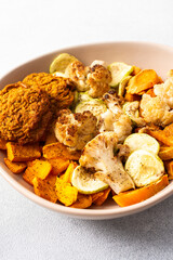 Colorful bowl of rice with rhubarb fried eggs, baked sweet potato, cauliflower, zucchini, and meat fritters alongside a fresh salad. Enjoy a nutritious and flavorful meal