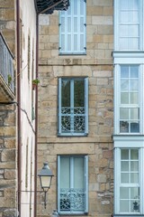 Traditional Stone Building Facade Featuring Light Blue Windows and Ornate Iron Railings in a Spanish Town