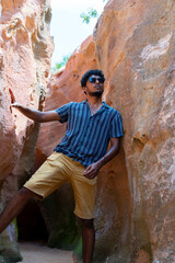 A man in a blue shirt and yellow shorts stands in a cave