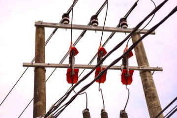 High-voltage electrical power lines and cables run from a massive metal tower pylon against a blue sky