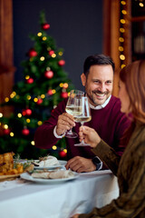 Warm Holiday Toast: Couple Enjoys Wine And Dinner By Christmas Tree In Cozy Home Setting