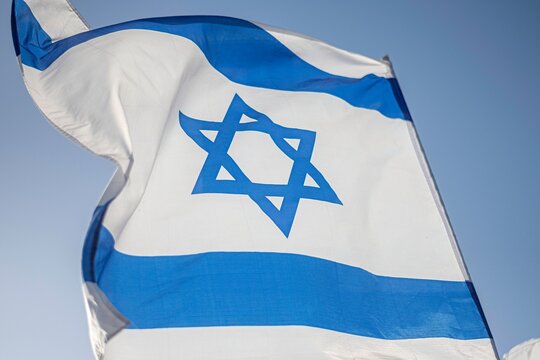High resolution close up color image of an Israeli flag in the wind with a blue background - Powered by Adobe