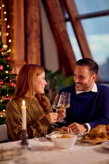 Couple Celebrating Christmas Dinner At Cozy Home With Wine Glasses And Christmas Tree