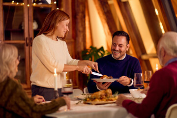 Warm Family Dinner Scene As Host Serves Plate During Holiday Gathering