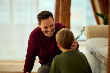 Warm Family Moment: Father Comforts Son With Laughing Conversation In Cozy Home Living Room