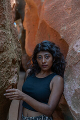 A woman is standing in a cave with her arms around a large rock