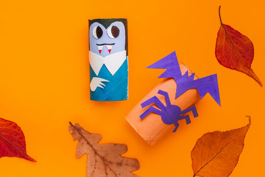 Halloween monsters from toilet paper roll tube, easy DIY handmade decorations idea. Paper toys zombie and vampire on yellow background. Kids creativity, easy eco craft, step by step, place for text