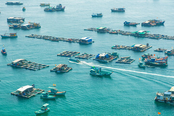 Floating fishing villages, farms and colorful fishing boats clustered in calm blue waters off the coast of Phu Quoc island, Vietnam. Drone view. Traditional fishing, sustainable living, slow travel  © samael334