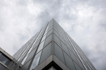 Blick nach oben in den Wolkenhimmel mit moderner Fenster Geb&auml;ude Fassade im Vordergrund