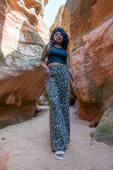 A woman wearing leopard print pants and a black tank top stands in a cave