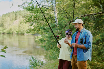 Caucasian young adult man and Caucasian girl hiking in forest, man holding map and girl examining compass, both wearing backpacks, standing among tall trees, exploring nature