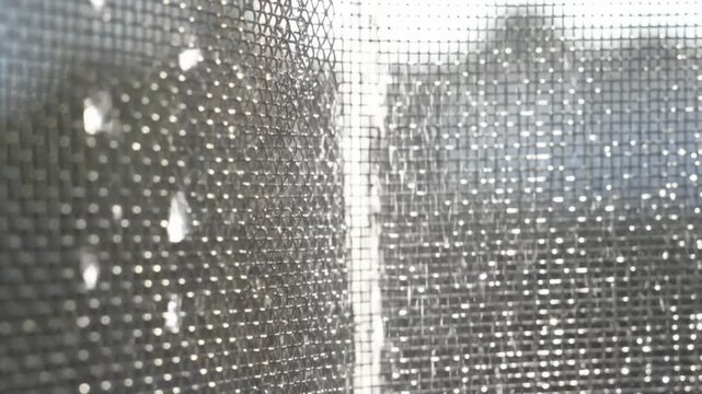 Water Drops Cascading Down a Window Screen During a Rainstorm