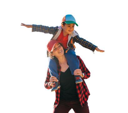 Happy little boy sitting on mom's neck spreads hands like airplane against transparent background , traveling. Family leisure outdoors, childhood. Tourism. young woman plays with son.