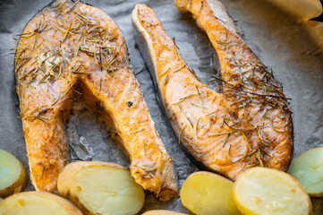 Baked salmon steaks with potatoes on a baking tray. Freshly cooked meal showing golden roasted potatoes and perfectly cooked salmon, ideal for healthy cuisine and culinary presentation.