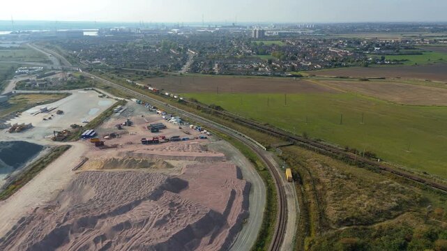Aerial drone view of huge freight train transporting cargo containers across landscape near Tilbury UK