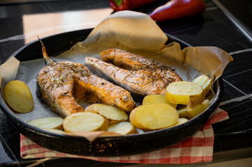 Baked salmon steaks with potatoes on a baking tray. Freshly cooked meal showing golden roasted potatoes and perfectly cooked salmon, ideal for healthy cuisine and culinary presentation.