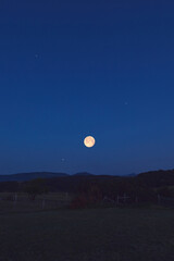 Full Moon with stars, planets and rural countryside tree silhouettes.