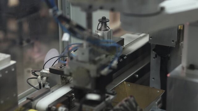 Close-up of an industrial robotic system featuring a gripper, sensors, and automated mechanical components on a production line. No visible branding or logos