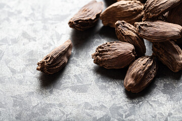 Close-up of dried black cardamom pods on a light grey background, detailed texture and natural shadows. Exotic spices and culinary ingredients. Ayurvedic treatment.