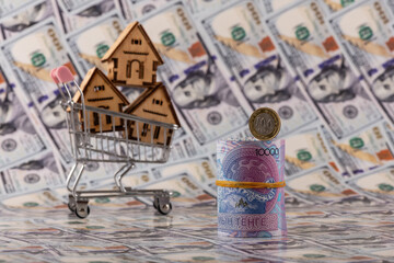 10,000 Kazakhstani tenge bills and symbolic wooden houses in a shopping cart against a backdrop of...