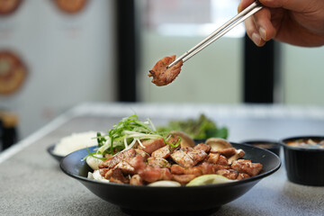 직화 돼지목살을 젓가락으로 집은 모습