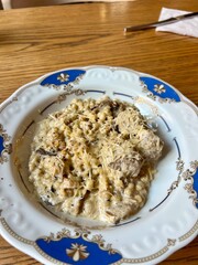 Ptitim pasta with chicken in a creamy sauce on a blue-rimmed plate lunch on the table