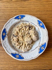Ptitim pasta with chicken in a creamy sauce on a blue-rimmed plate lunch on the table
