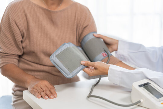 Doctor measuring elderly woman's blood pressure, monitoring hypertension and general health during a medical check up