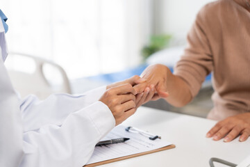 Doctor examining a patient's hand at a clinic, providing care and support during a healthcare consultation
