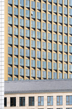 Modern architectural building facade with golden tone windows showing geometric pattern, rhythm, and repetition emphasizing balance, proportion, and refined contemporary design structure.