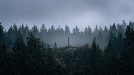 Christian cross stands on a hill, silhouetted against fog in forest, moody atmosphere